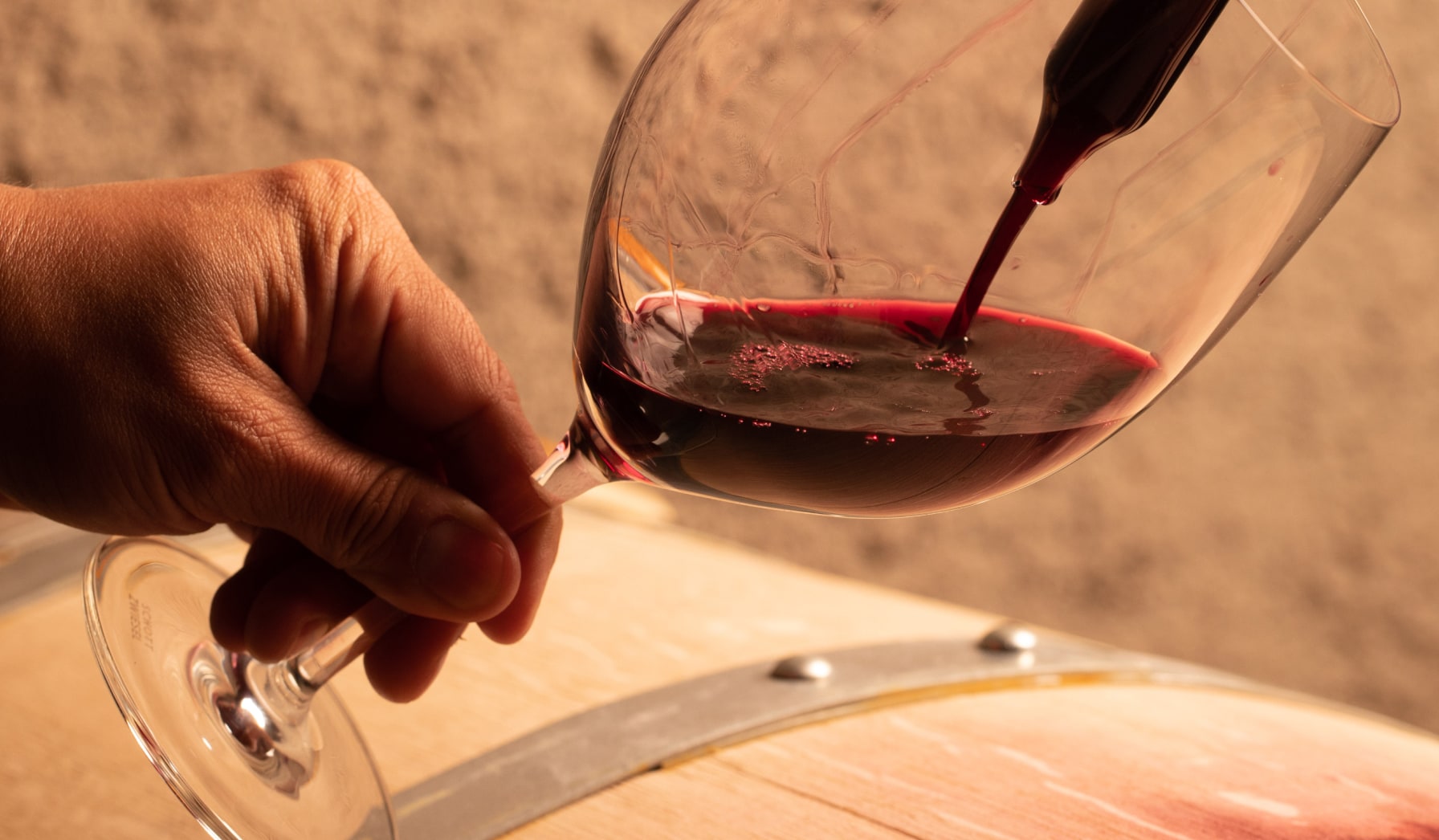 Wine being poured into glass next to barrel