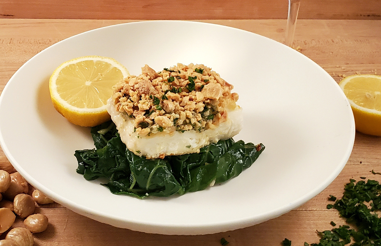 Almond crusted Halibut beside a glass of white wine